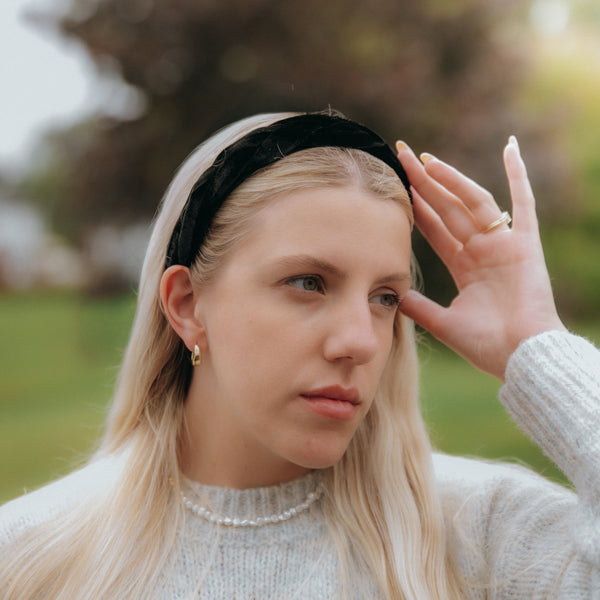 Woman with long blonde hair wearing a black headband outdoors