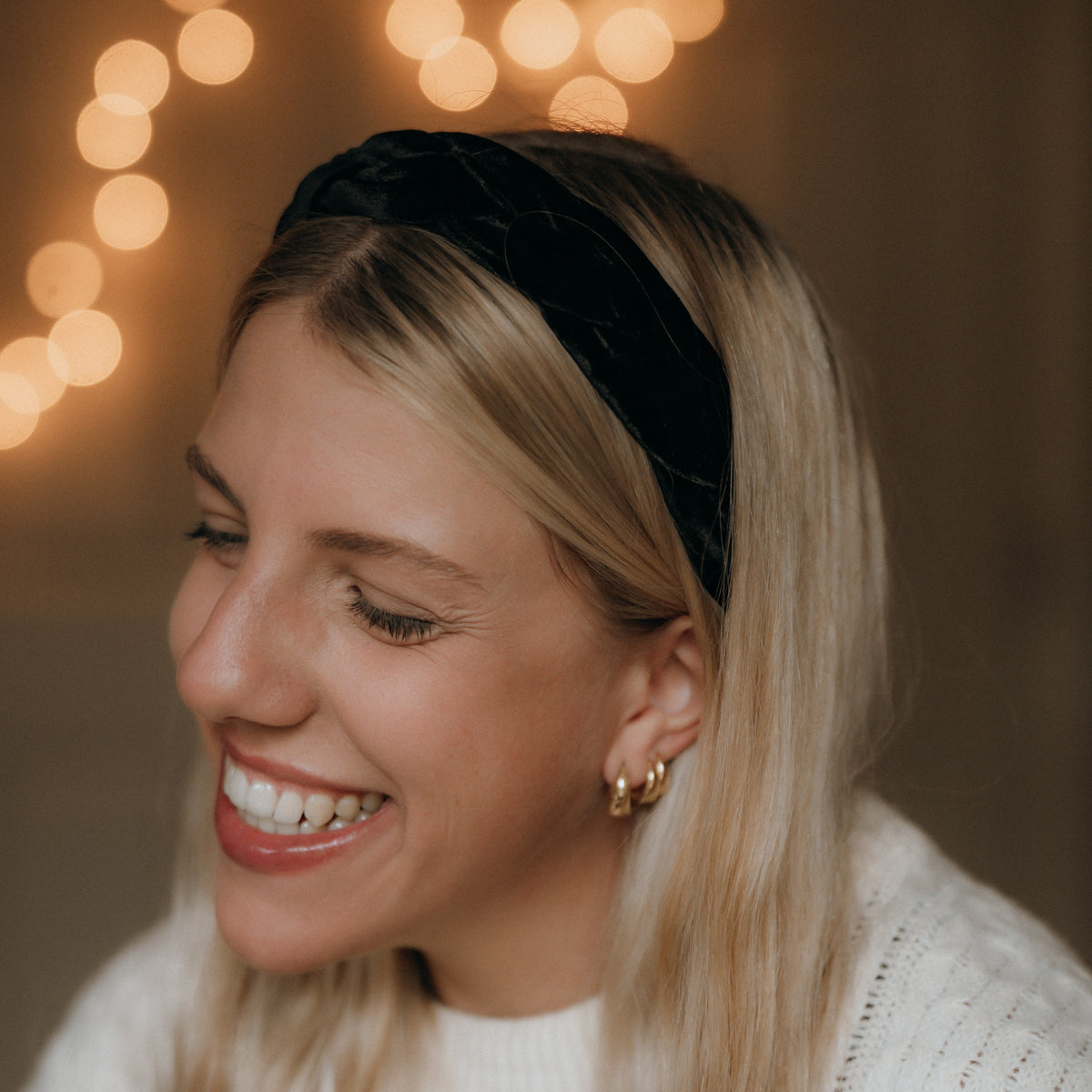 Woman wearing a black headband with blurred lights in the background