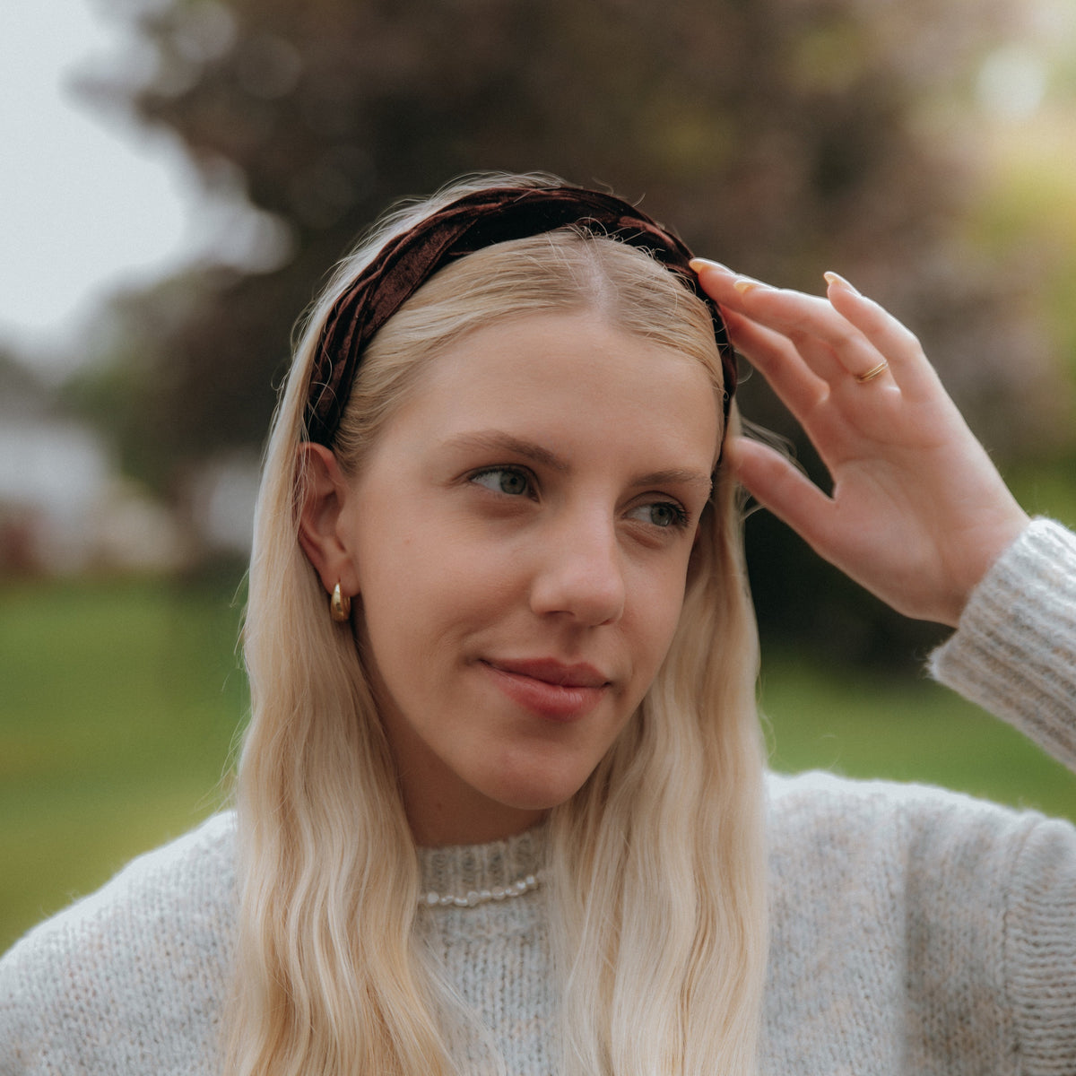 Woman with long blonde hair wearing a headband outdoors