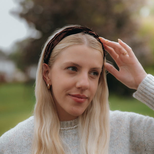 Woman with long blonde hair wearing a headband outdoors