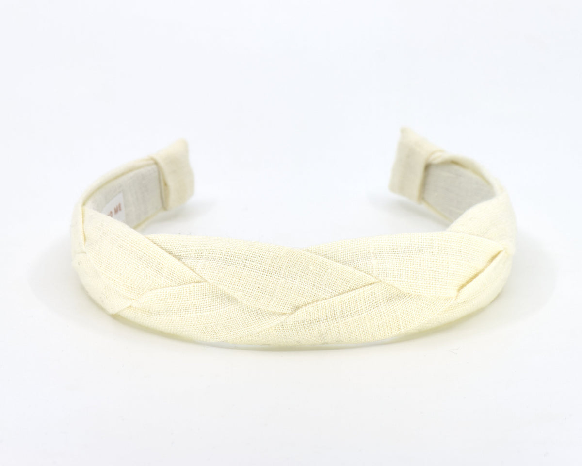 A braided fabric headband in a pale cream or off-white color, shown on a plain white background.