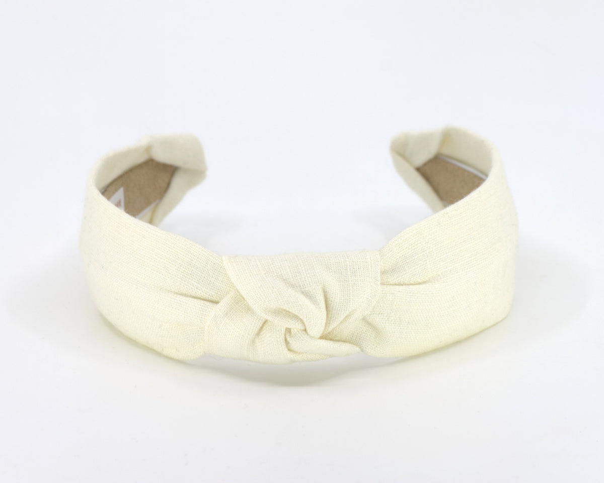 A wide cream linen fabric headband with a knotted center detail, shown on a plain white background.
