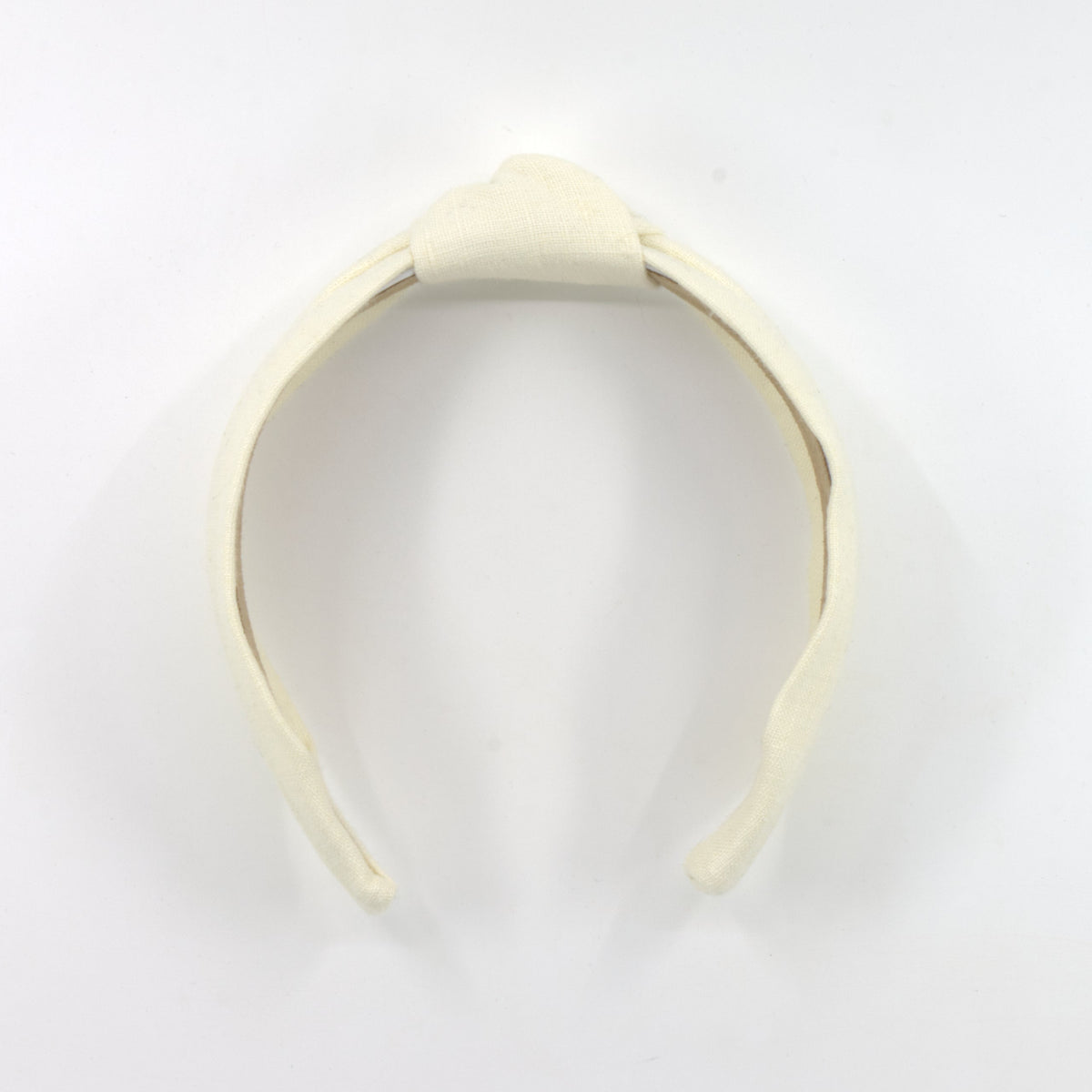 A cream-colored fabric headband with a knotted top detail, displayed on a plain white background.