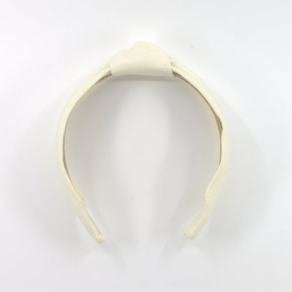 A cream-colored fabric headband with a knotted top detail, displayed on a plain white background.