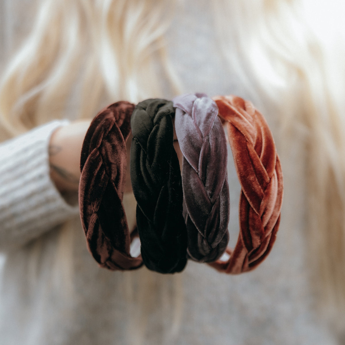 Set of four velvet hair ties in brown, green, and pink held by a person with blonde hair.
