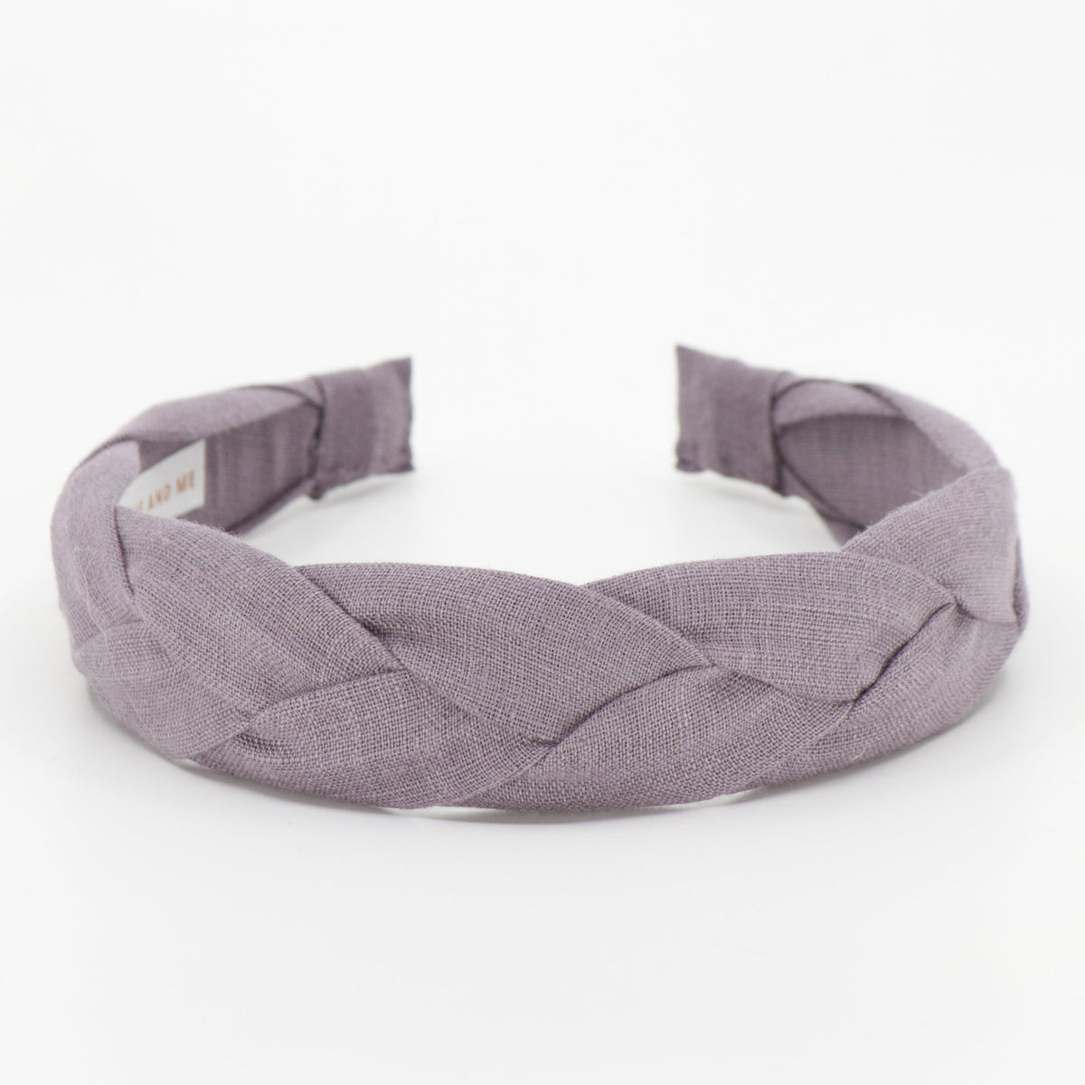 A wide braided fabric headband in a muted dusty lavender-purple color, photographed on a seamless white background.