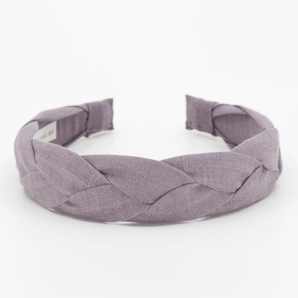 A wide braided fabric headband in a muted dusty lavender-purple color, photographed on a seamless white background.
