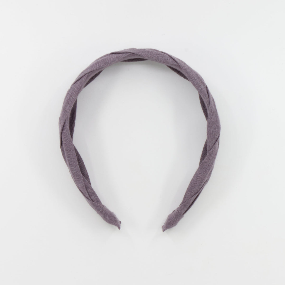 A braided fabric headband in a muted dusty purple color, photographed against a seamless white background.