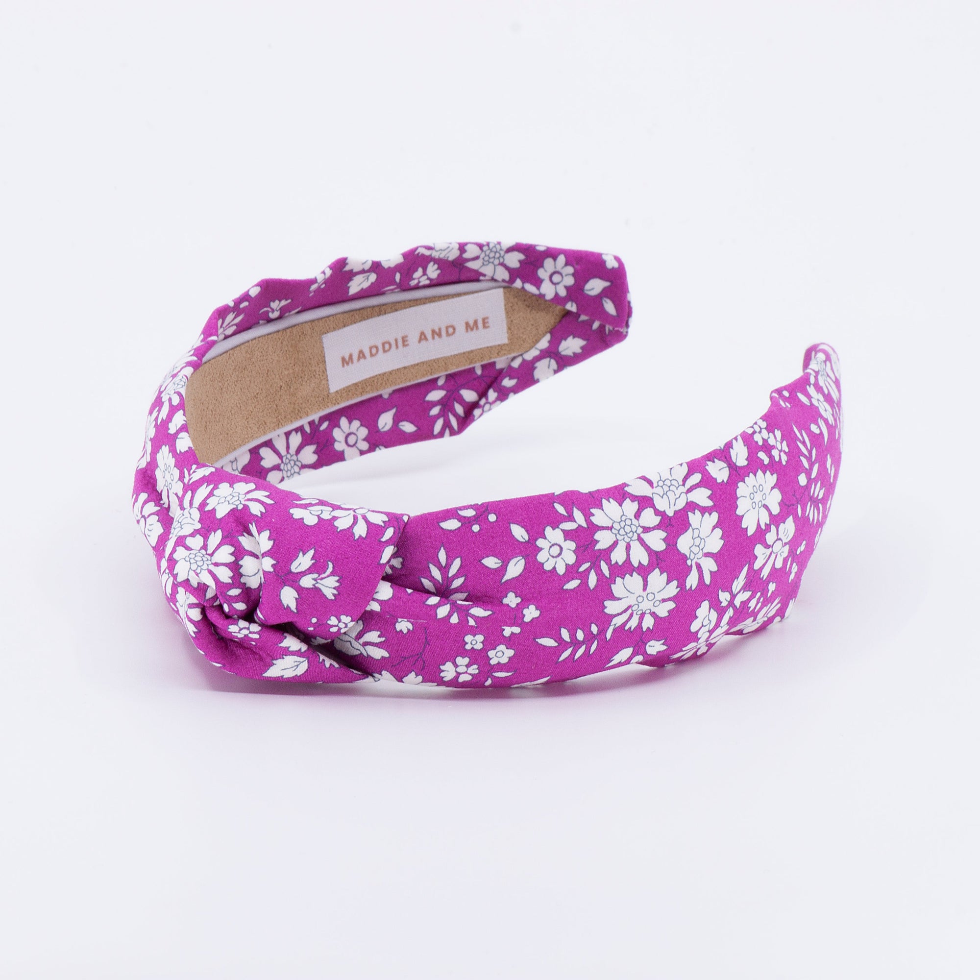 Bright pink floral headband with a visible brand label on a white background