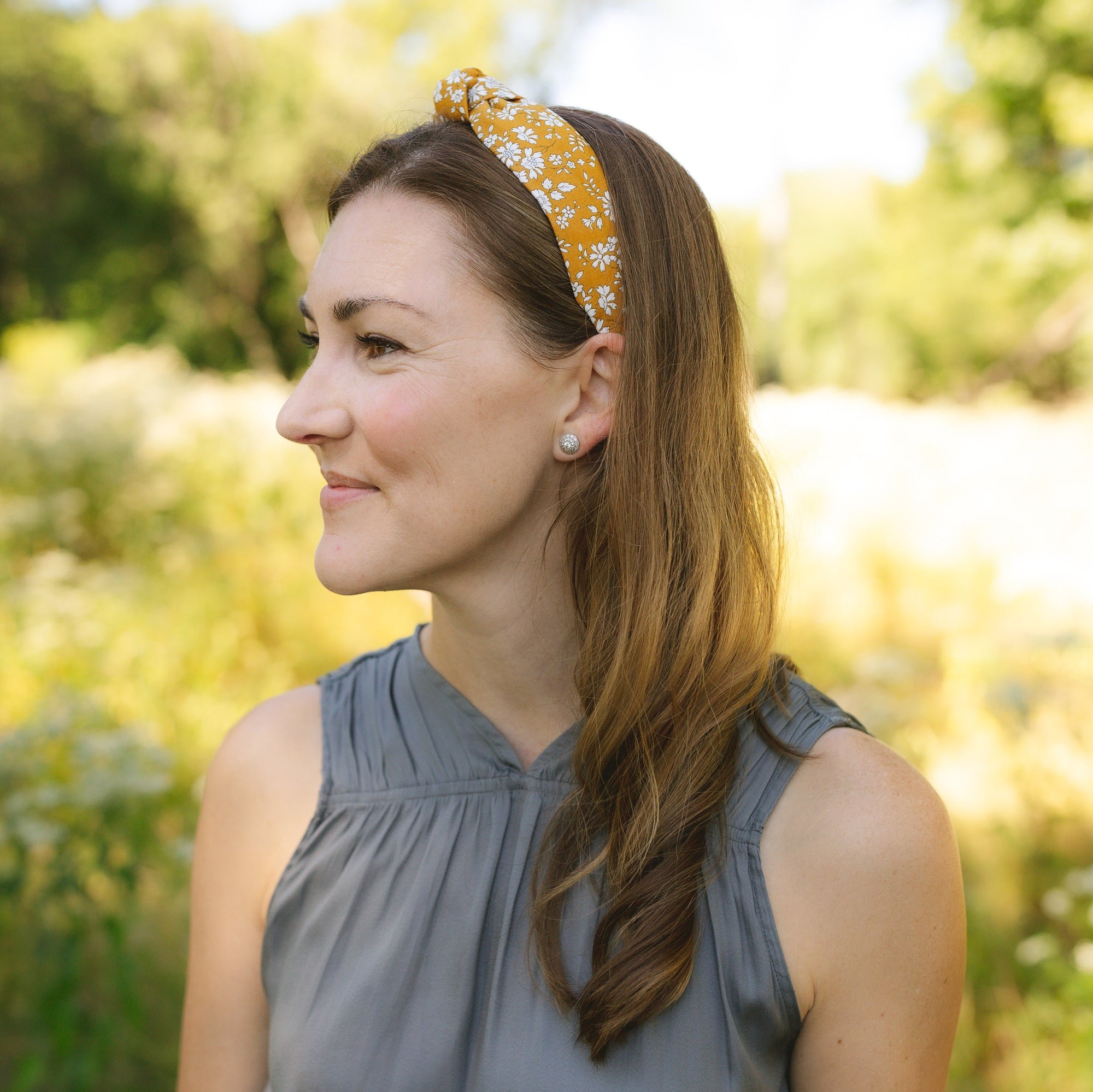 Woman wearing a floral knotted headband in a natural setting